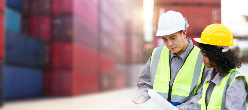 Container yard workers inspecting cargo containers together - Powered by Adobe