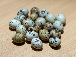 Obraz premium Fresh quail eggs in a wooden table close-up. Fresh quail eggs on a brown wooden table. Raw quail eggs close-up on a culinary background. Concept of preparation for cooking, healthy eating. 