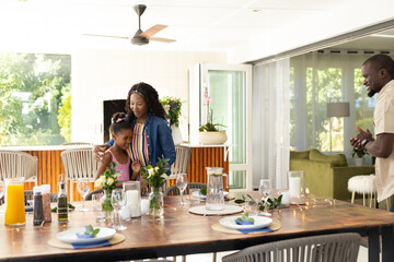 Family enjoying quality time setting dining table together at home, smiling warmly