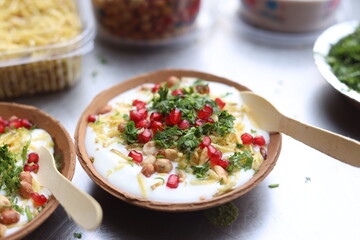 Indian Chaat Dahi Bhalle with Curd and Sweet Sauce on banana leaf with indian backdrop