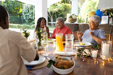 Laughing and sharing joyful moments, African American family having outdoor meal together