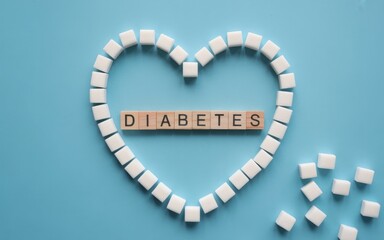 Fototapeta premium Heart shape made of sugar cubes and diabetes word on blue background, top view