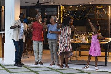 Family celebrating together outdoors, raising glasses and dancing joyfully at night