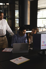 Collaborating on project, business professionals using laptop and charts in office