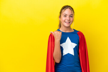 Super Hero little girl isolated on yellow background pointing to the side to present a product © luismolinero