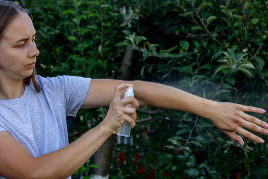 Woman applying insect repellent spray on her hand. Concept of preventing mosquito bites