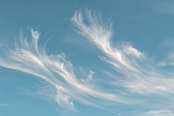 Delicate, wispy clouds drift across a pale blue sky