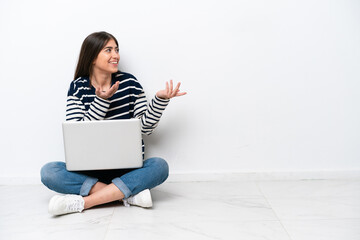 Young caucasian woman with a laptop sitting on the floor isolated on white background with surprise...