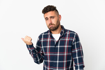 Naklejka premium Caucasian man isolated on white background unhappy and pointing to the side