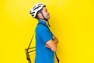 Young handsome man with thermal backpack over isolated yellow background in lateral position