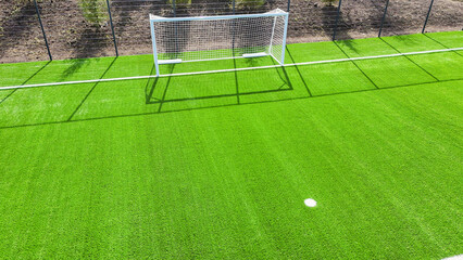 A soccer field with a goal and a net. The grass is green and the field is well maintained