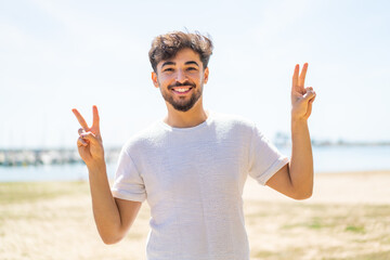 Handsome Arab man at outdoors showing victory sign with both hands