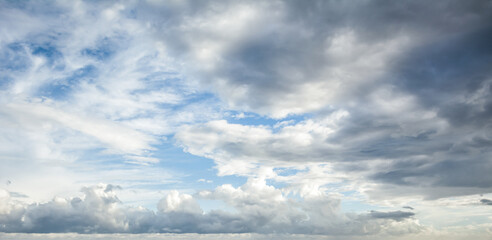 Obraz premium White fluffy clouds scattered across a deep blue sky creating a bright and airy weather background with natural light