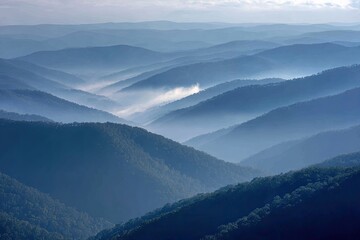 Fototapeta premium Misty mountain ranges, soft blue hues