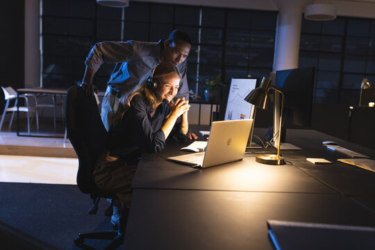 Collaborating on project, colleagues focused on computer screen in office working late