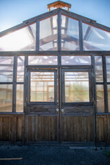 Fototapeta premium Vertical image of wooden greenhouse with emphasis on the doors and sun pouring through.