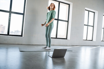 Young woman practices fitness routine in spacious, bright room with large windows