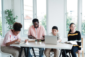 African American man is teacher or tutor teaching  with laptop for Caucasian students or pupils group in classroom at school. Education and technology concept