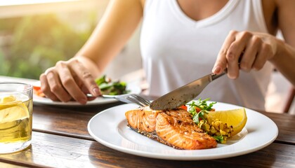 Woman eating a healthy salmon fillet with lemon and salad outdoors.