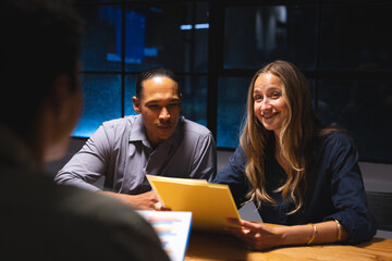 In office, business professionals discussing documents during late-night meeting