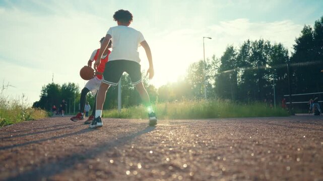 Active sport, african american boys playing streetball in summer, slow motion. Black guys exercising on outdoors basketball court in sunny day, intense practicing attack and defense in streetball