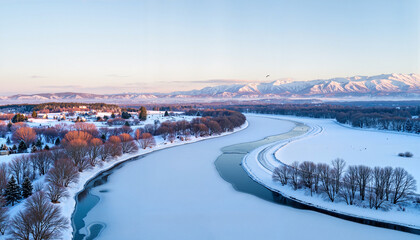 Snow-covered river meandering through winter landscape with mountains  