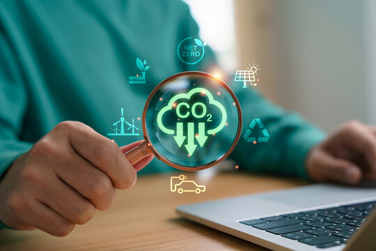 Hand holding magnifying glass showing CO2 emission reduction for net zero, renewable energy and eco-friendly sustainability concept of environmental protection and green technology.