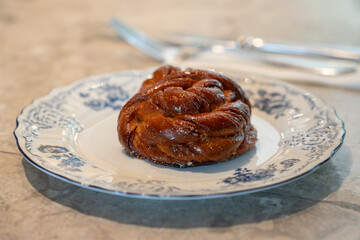 Freshly baked cinnamon bun with glossy caramelized crust served on a vintage blue-and-white porcelain plate