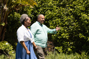 Senior couple walking in garden, enjoying sunny day and lively conversation
