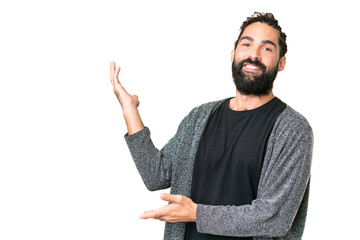 Young man with beard over isolated chroma key background extending hands to the side for inviting...