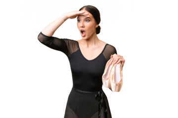 Young caucasian woman practicing ballet over isolated background doing surprise gesture while looking to the side