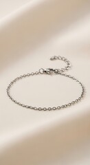 Minimalist silver chain bracelet displayed on a smooth satin background