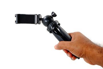 Naklejka premium Hand holding a mobile tripod stand on white background closeup view, Holding a mini selfie stick on white background