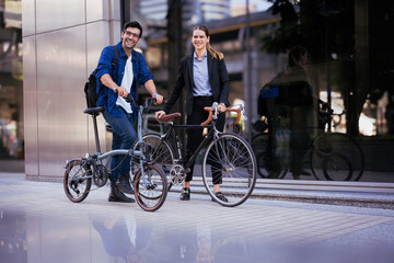 Commuting to work with bicycle. Businessman businesswoman cycling to office in downtown district....