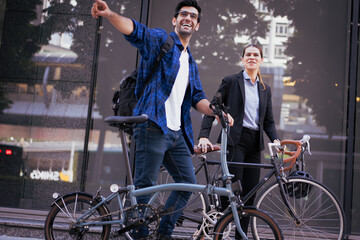 Commuting to work with bicycle. Businessman businesswoman cycling to office in downtown district....