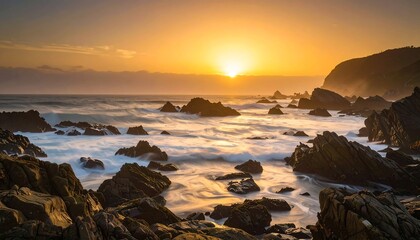 Rocky beach at sunset with waves crashing, bright sunburst over the water, and hilly background