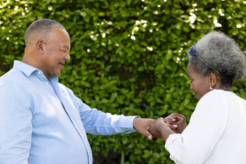 Senior couple enjoying outdoor moment, smiling and holding hands in garden