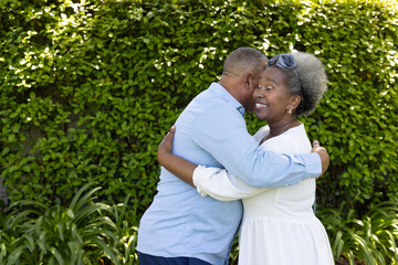 Senior couple embracing warmly in garden, enjoying joyful moment together
