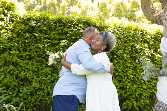 Senior couple embracing warmly in garden, enjoying sunny day together