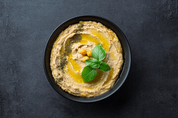 A traditional dish or appetizer hummus or baba ghanoush on black background	