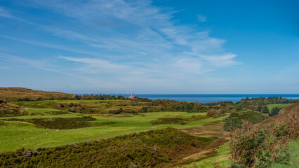Fototapeta premium Weite Hügellandschaft mit Blick auf Glengorm Castle am Bildrand – spätsommerliche Szene auf der Isle of Mull, Schottland, aufgenommen im August 