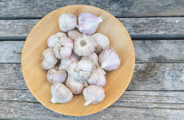 Fresh garlic bulbs in wooden bowl on rustic table, natural organic ingredient for cooking and traditional cuisine