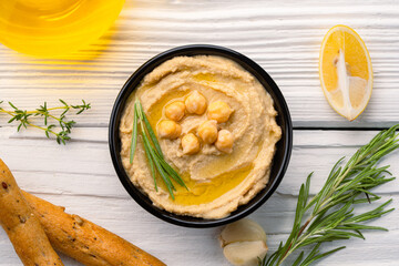  A traditional dish or appetizer hummus or baba ghanoush on white wooden background