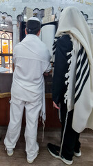 A Bar Mitzvah boy and his father standing by the Torah ark
