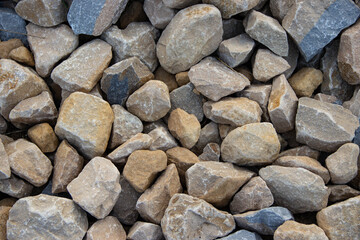 Natural stones in various shapes and sizes, showcasing earthy tones and textures, create a visually appealing surface, ideal for landscaping and construction projects