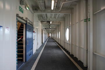 Interior corridor of a ferry showcasing clean lines, circular windows, and industrial design elements, creating a sense of spaciousness and travel