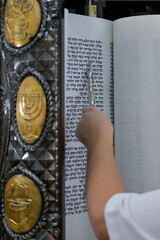 A bar mitzvah boy reading from the Torah scroll in a synagogue.