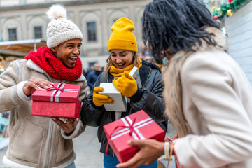 Friends exchanging christmas gifts at a christmas market
