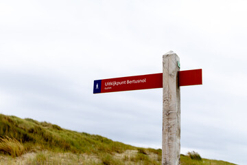 Texel, Netherlands - August 31, 2025: Directional signpost for hiking trail at Uitzichtpunt Bertusnol in natural landscape with cloudy sky
