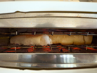 Fresh Bread Toasting Inside Electric Toaster with Glowing Coils